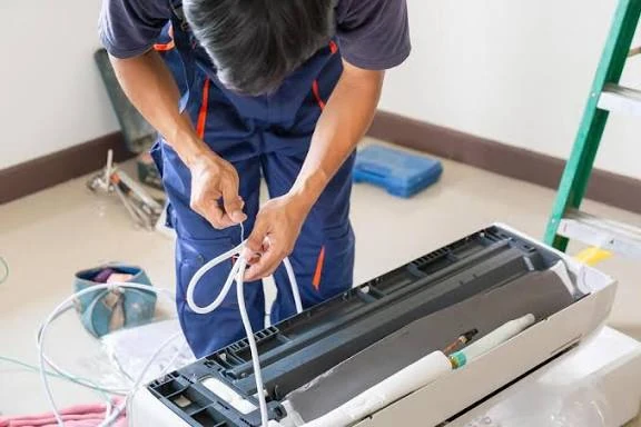 Technician servicing the open housing and tubing of an indoor AC unit